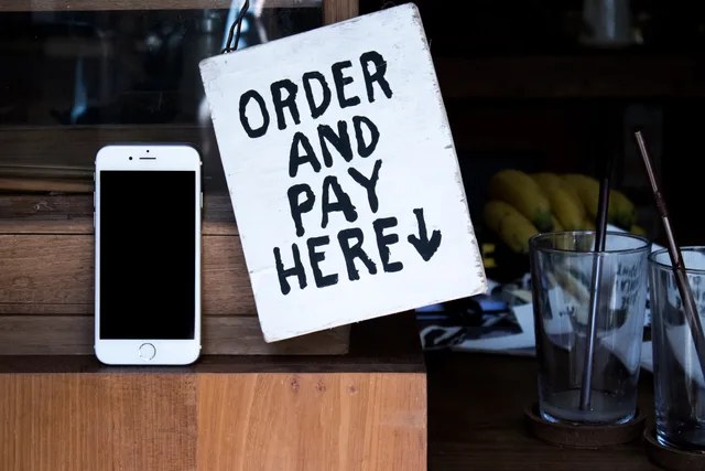A phone next to an 'Order and Pay Here' sign in a cozy indoor setting, perfect for business use. DTC growth decisions